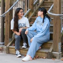 Two international students sitting outside on campus talking together