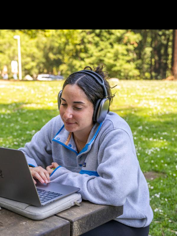 Student with a laptop and headphones outside