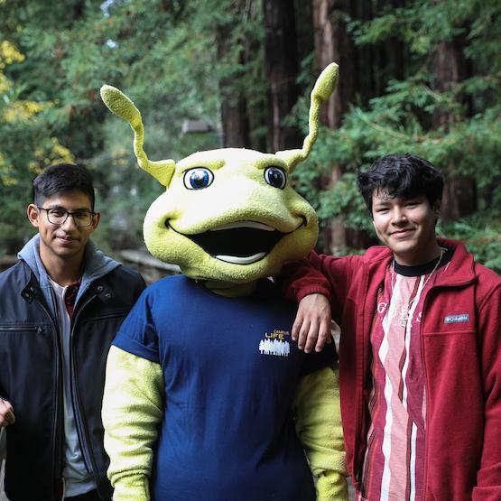 Sammy Slug mascot flanked by 2 students