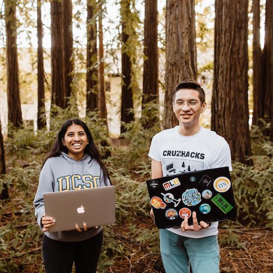 Students outside in the redwoods holding laptops