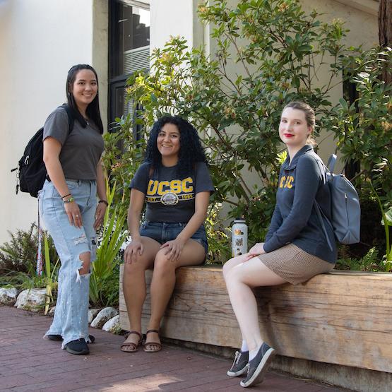 Três estudantes do lado de fora do Crown College.