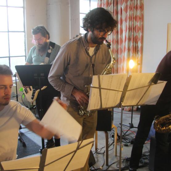 A band of five individuals performing on mic using several instruments