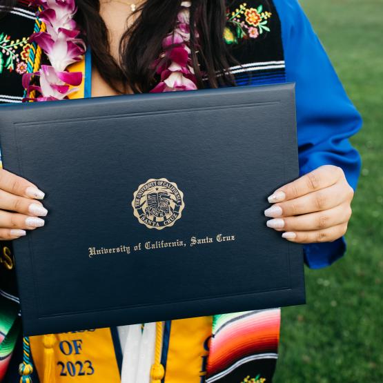 Isang indibidwal na may hawak na folder na may mga salitang "University of California, Santa Cruz" dito