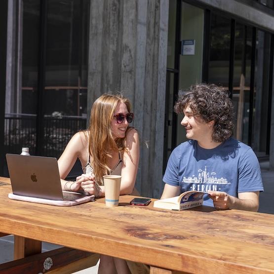 Two students at a picnic bench on campus