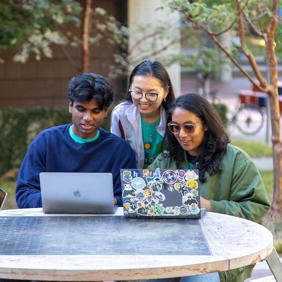 Students studying together outside with laptops